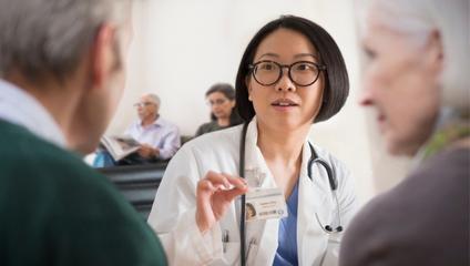 Image of female doctor in white lab coat speaking with a patient and support person to boost emergency department efficiency and patient satisfaction