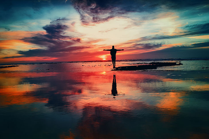 Person on beach with a colorful sky