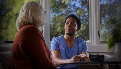 Male Vituity Medical Professional In Blue Scrubs Smiling Consulting Patient