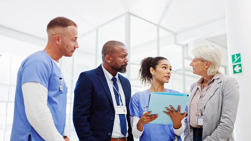 Healthcare professionals and administrators discussing patient care in a modern hospital setting.