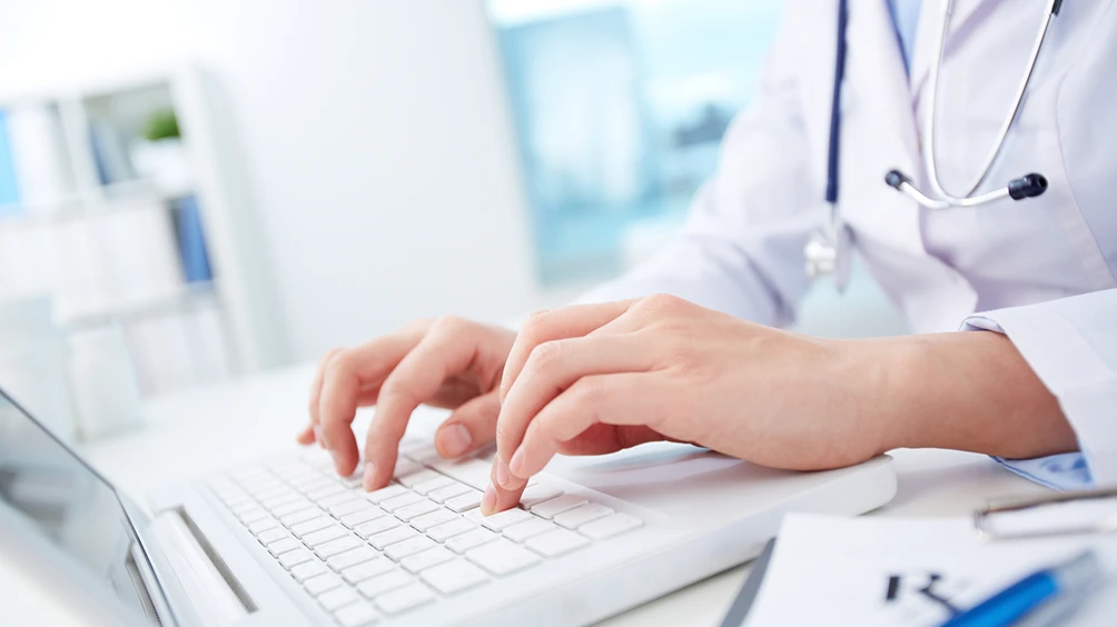 physician typing on laptop