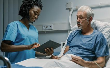 Vituity nurse talking with patient in hospital bed