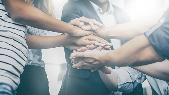 Several people put their hands together to show teamwork.