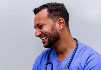 male Vituity nurse smiling in blue scrubs