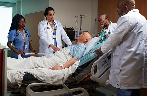 four Vituity medical professionals consulting with patient in hospital bed