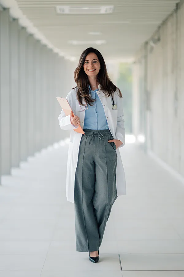 Confident doctor smiling and walking in hospital corridor
