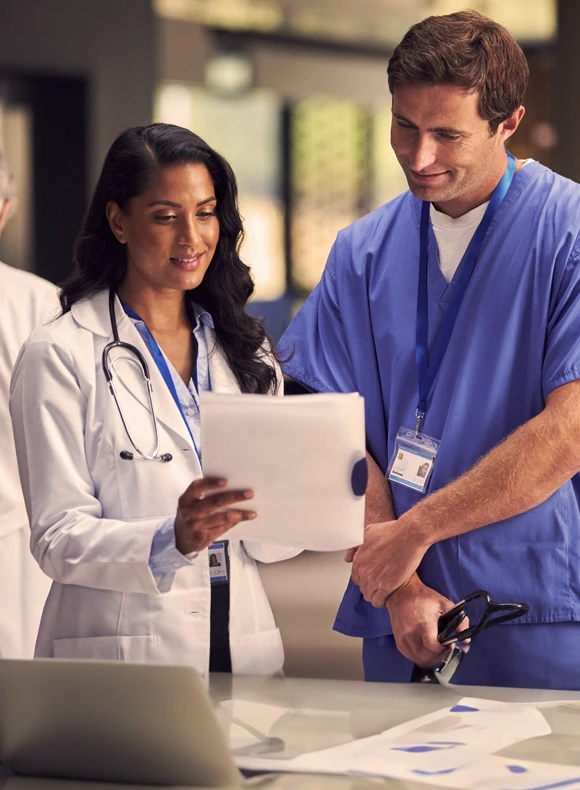 Resident physician in blue scrubs with a tablet in his hand and stethoscope around neck