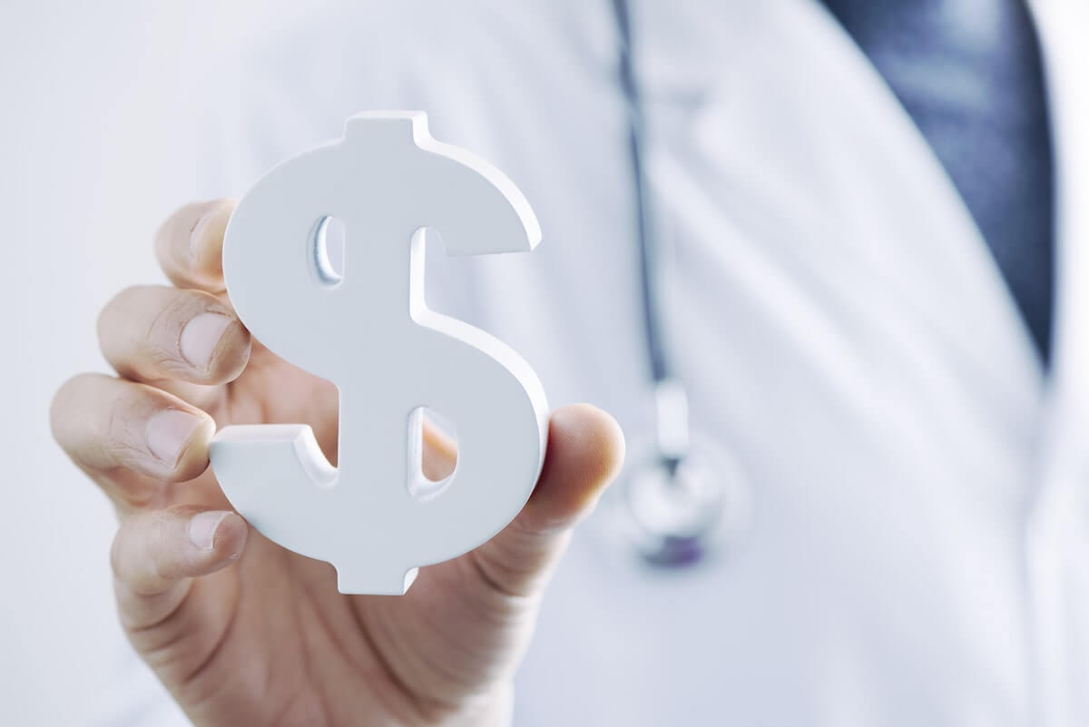 Doctor in white coat holding up a dollar sign