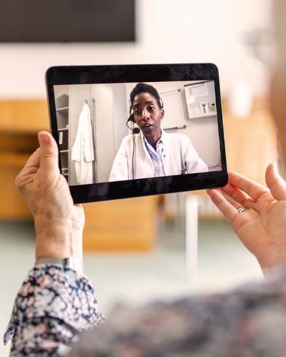 Telepsychiatry virtual visit patient holding tablet with physician on screen