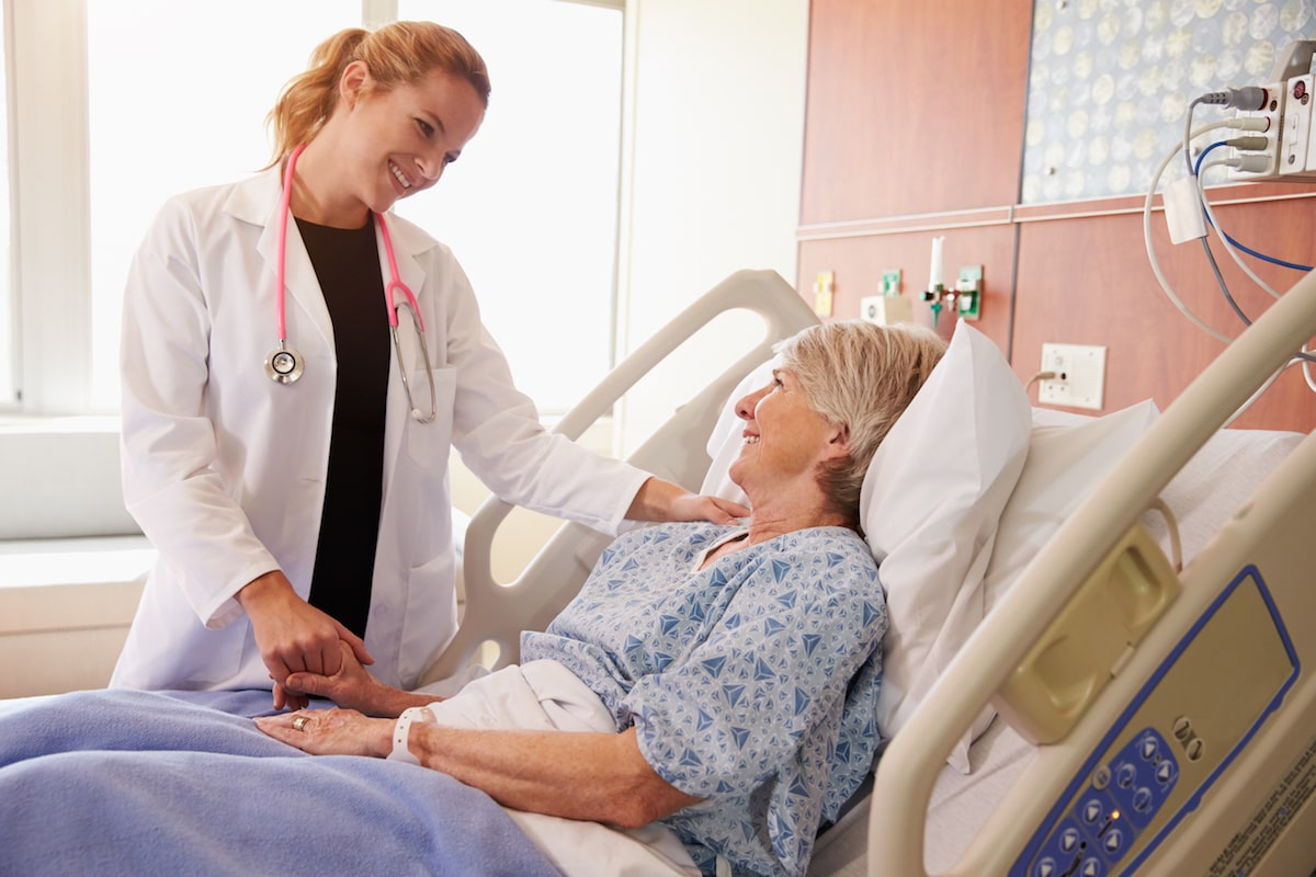 woman hospitalist physician examining woman patient in hospital bed