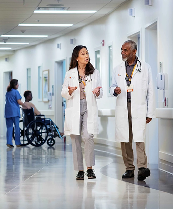 Physicians in dIscussion walking thru hospital