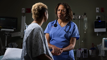 female vituity medical professional in blue scrubs holding patient's hand during consultation