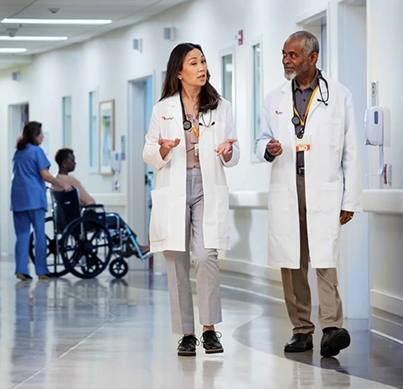 Physicians in dIscussion walking thru hospital