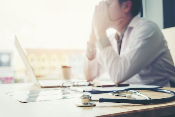 Doctor on his laptop dealing with physician burnout