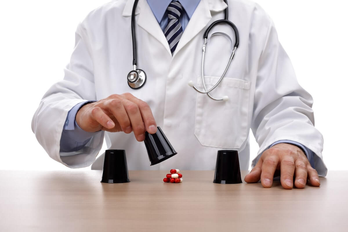 Doctor in a white coat playing a shell game with pills