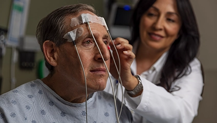Female Vituity Physician In White Labcoat Adjusting Sensors On Patients Head