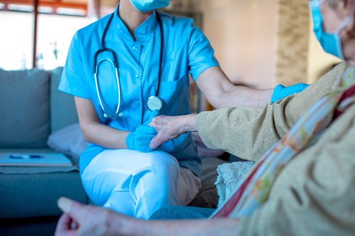 Provider holds a patient’s hand with patient-centered care.