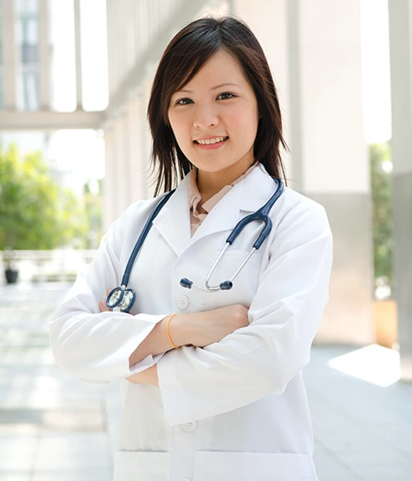 Physician fellow smiling while standing outside of hospital with arms crossed