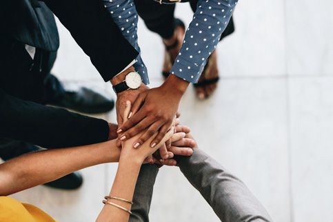 Several people put their hands together to show teamwork.